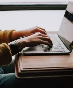 close up of someones hands typing on a laptop