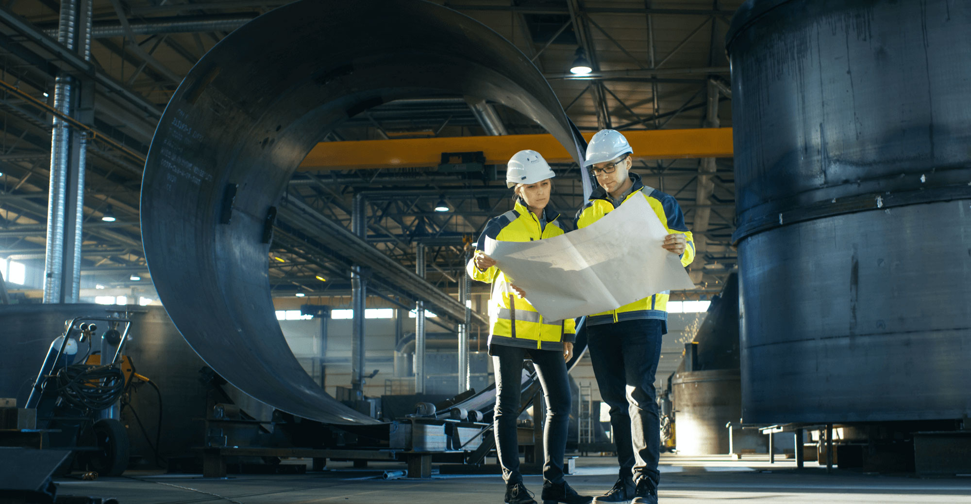 man and woman looking at detailed drawings standing in a huge warehouse