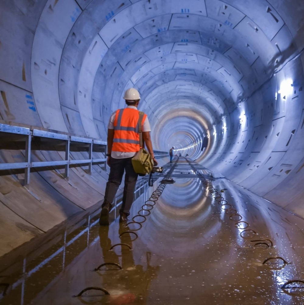 Engineer walking down a tunnel wearing a hard hat and safety vest