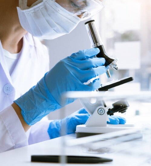 woman looking down a microscope in lab