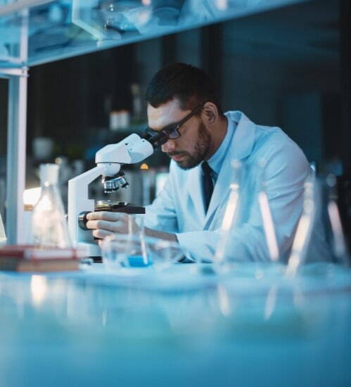 man looking down a microscope in lab
